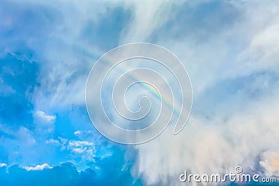 Natural rainbow over blue sky and white clouds Stock Photo