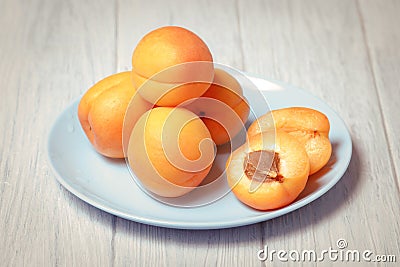 Natural ripe yellow apricots on porcelain plate sliced half with fruit pit Stock Photo
