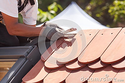 Natural roof tile instaalation. Roofer builder worker use ruller to measure the distance between the tiles. Stock Photo