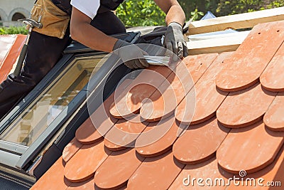 Natural roof tile instaalation. Roofer builder worker use ruller to measure the distance between the tiles. Roof with mansard wi Stock Photo