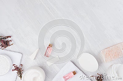 Natural spa white and pink cosmetics products and bath accessories with pink flowers as frame on white wood board, top view. Stock Photo