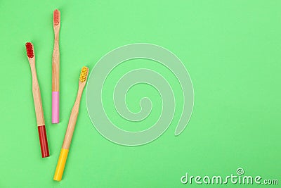 Natural toothbrushes made with bamboo on green, flat lay. Space for text Stock Photo