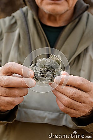 Natural unprocessed pieces of mica minerals in the hands of a man in a natural deposit Stock Photo