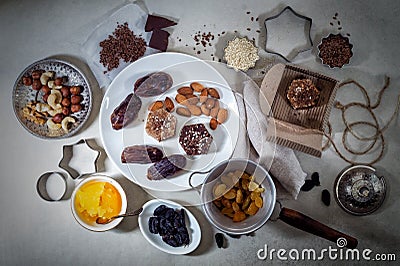 Natural useful sweets from dates, nuts, honey and raisins on a white plate. These ingredients are next on the table Stock Photo