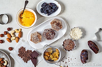 Natural useful sweets from dates, nuts, honey and raisins on a white plate. These ingredients are next on the table Stock Photo