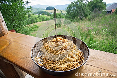 Natural view and pan with Italian pasta with tomato and fork. Spaghetti food on terrace of rural home Stock Photo