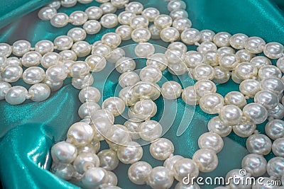 Natural White Pearls in the water on a blue silk texture close-up. Pendants on the neck. Stock Photo