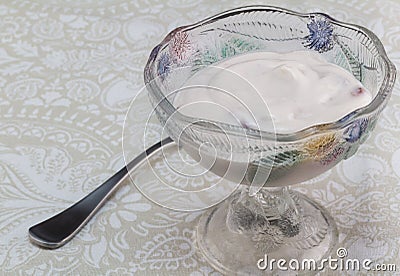 Natural yoghurt with berries in glass dessert bowl on patterned Stock Photo