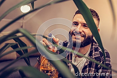 Delighted bearded man caring about his plant Stock Photo