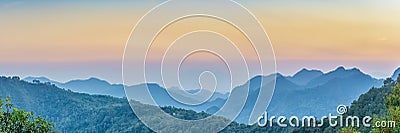 Nature Web Banner. Mountain view sunset panorama view of many hill and green forest cover with soft mist with colorful sky Stock Photo