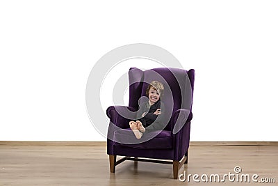 Naught child sitting with arms crossed on armchair Stock Photo