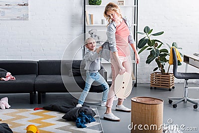 naughty daughter holding cardigan of tired mother cleaning Stock Photo