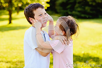 Naughty little girl pinching cheeks of her brother Stock Photo