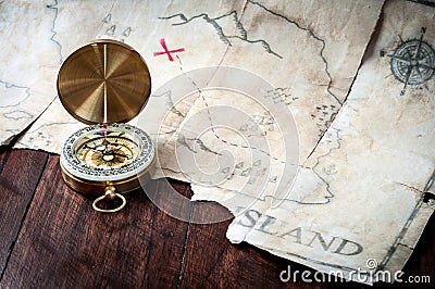 Nautical compass in front of fake pirates treasure map on wooden table Stock Photo