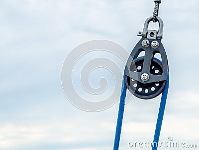 Nautical pulley and a blue cable in the cloudy day Stock Photo