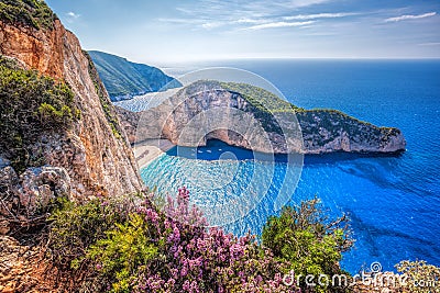 Navagio beach with shipwreck and flowers against sunset on Zakynthos island in Greece Stock Photo