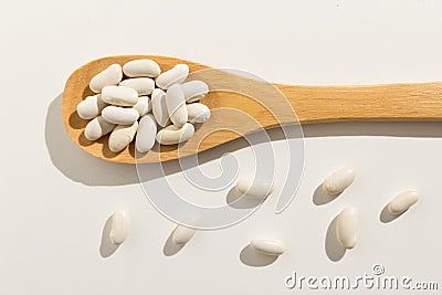 Navy Bean legume. Healthy grains on a wooden spoon. White background. Stock Photo