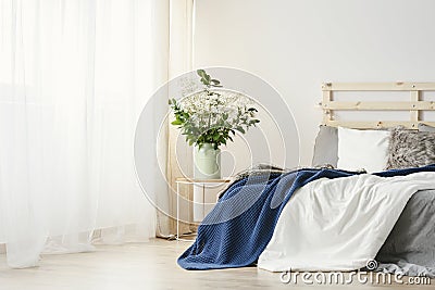 Navy blue blanket thrown on double bed with lights on bedhead st Stock Photo