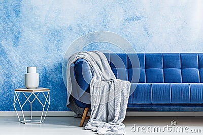 Navy blue sofa with gray blanket and openwork metal side table w Stock Photo