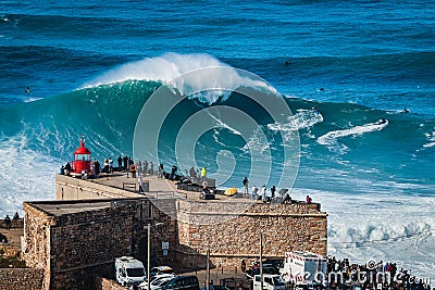 Nazare, Portugal, Surfer Riding Giant Wave in Front of Nazare Lighthouse Stock Photo