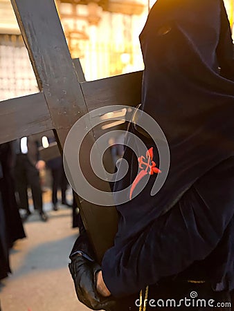 Nazarene carrying a wooden cross during the Holy Week procession in Seville, Spain Stock Photo