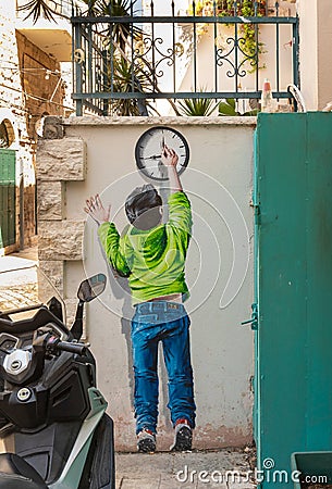 A drawing depicting a boy moving the hands of a clock is painted on the wall of a house of Nazareth old city in northern Israel Editorial Stock Photo