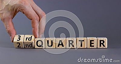From 2nd to 3rd quater symbol. Businessman turns cubes and changes words `2nd quater` to `3rd quater`. Beautiful grey table, g Stock Photo