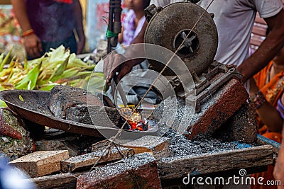 ndian man hands roasting corn, the indian street food at street market Stock Photo