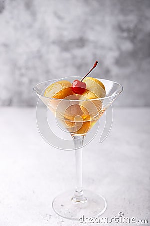 Neapolitan Rum baba or baba au rum in a martini glass with a cocktail cherry on a gray background. Small yeast cakes. Stock Photo