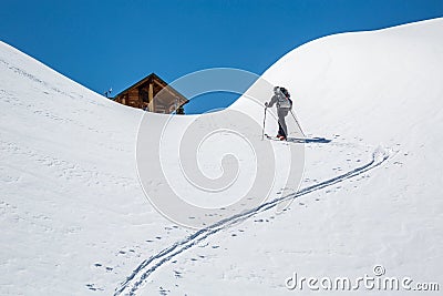 Skier skinning uphill, hiking toward a backcountry ski hut in the Rocky Mountains of British Columbia, Canada Stock Photo