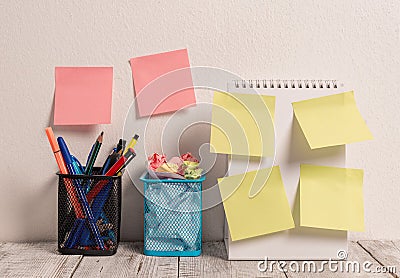 Neat Workplace with 6 Empty Colored Stick Pad Notes Put on Both White Wall and Open Spiral Notebook with 2 Full Pencil Stock Photo