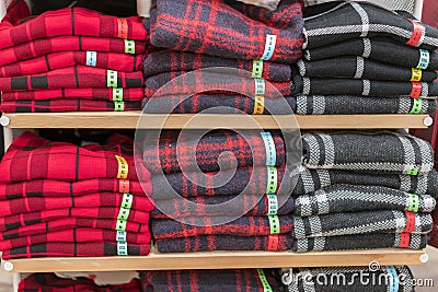 Neatly folded clothes. Rack of clothes with warm. Wooden cabinet with a stack of sweaters. Coloured clothing. Neat stacks of Stock Photo