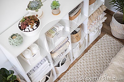 Neatly folded linen cupboard shelves storage at eco friendly straw basket placed closet organizer Stock Photo