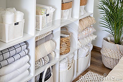 Neatly folded linen cupboard shelves storage at eco friendly straw basket placed closet organizer Stock Photo