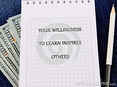 A neatly lined notepad displays an inspiring message about learning. Beside it, several hundred dollar bills and a Stock Photo