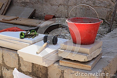 Necessary tools for construction - rubber hammer, bucket and gloves. Construction site in full swing. Discarded tiles. Workers Stock Photo