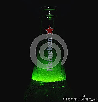 Neck of Heineken Lager Beer bottle full of foam. Neck of beer bottle with beer foam on dark background. Beer bubbles. Editorial Stock Photo