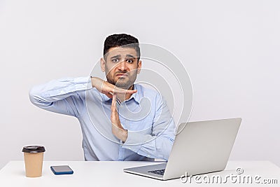 Need break! Upset man employee sitting office workplace with laptop on desk, looking imploring and showing time out Stock Photo