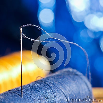 Needle and blue and yellow thread, shallow depth of field Stock Photo