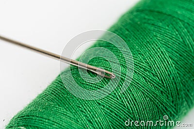 Needle head on the green thread over white background Stock Photo