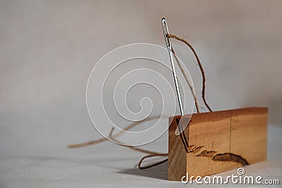 A needle with thread attached stays as nailed on a piece of colorful wood Stock Photo