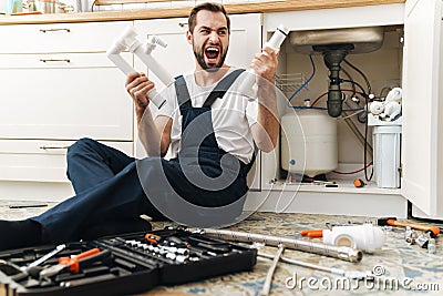 Negative emotional man plumber holding pipe Stock Photo