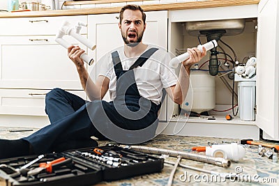 Negative emotional man plumber holding pipe Stock Photo