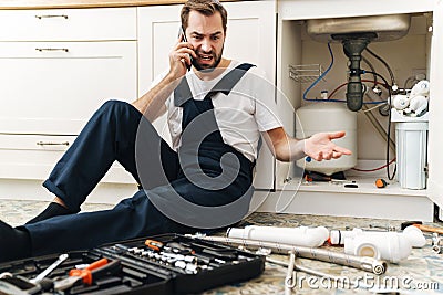 Negative man plumber work in uniform indoors Stock Photo