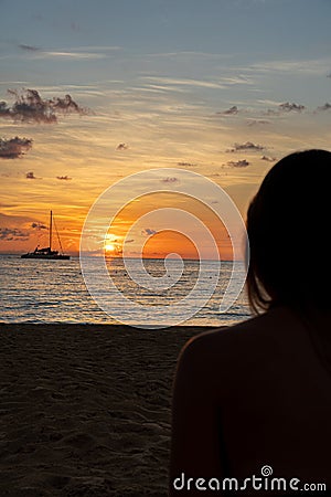 Women watches sailboat sail off into sunset Stock Photo