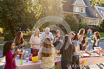 Neighbours talk and eat around a table at a block party Stock Photo