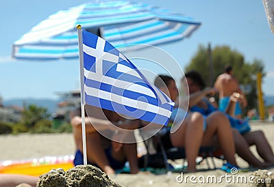 Little Greek flag in sand isolated with blurred people Editorial Stock Photo