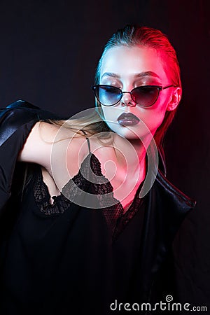 Neon close up portrait of young woman in sunglasses. Model posing in red and blue light Stock Photo