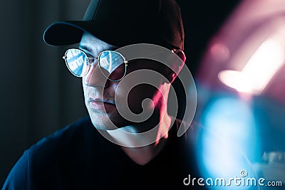 Neon light in glasses of a man. Futuristic cyber studio portrait. Techno glow and vibrant cyberpunk color. Male model. Stock Photo