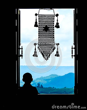 Neophyte at window (in partial silhouette) with thai hanging mo Stock Photo